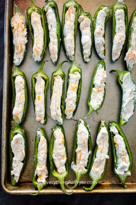 jalapenos stuffed with cheese mixture on a baking tray