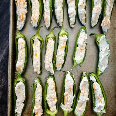 jalapenos stuffed with cheese mixture on a baking tray