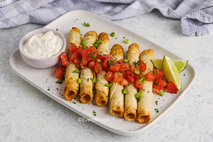 taquitos on a plate with tomatoes