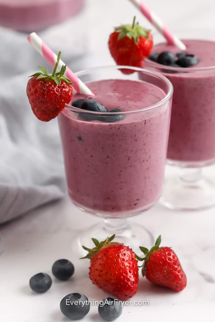 Berry smoothie in a glass with a straw and garnished with berries