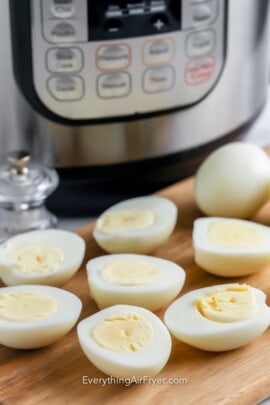 Hard boiled eggs sliced in half in front of an instant pot.