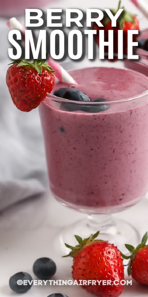 Berry smoothie in a glass with a straw and garnished with berries with text