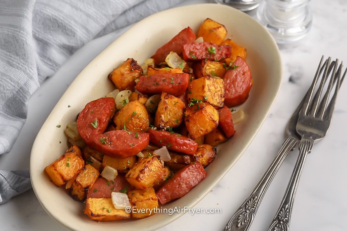 Air Fryer Butternut Squash and Sausage in a serving dish with serving utensils