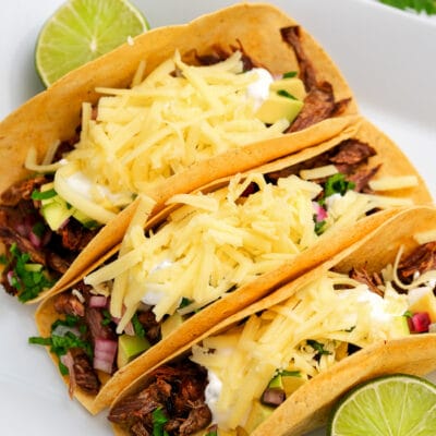 Three Air Fryer Brisket Tacos on a plate with lime wedges