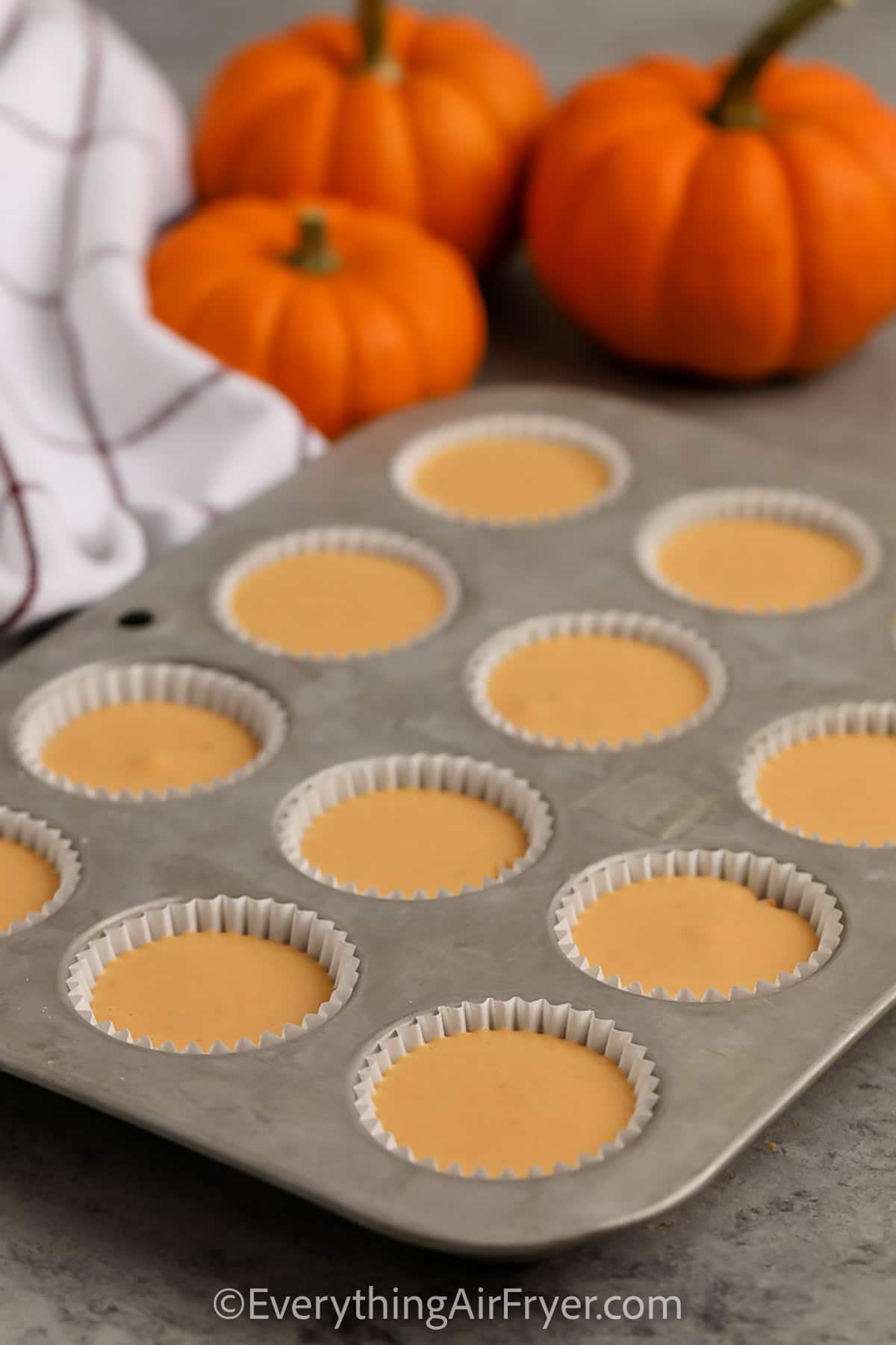 Mini Pumpkin Cheesecake batter poured in muffin tins