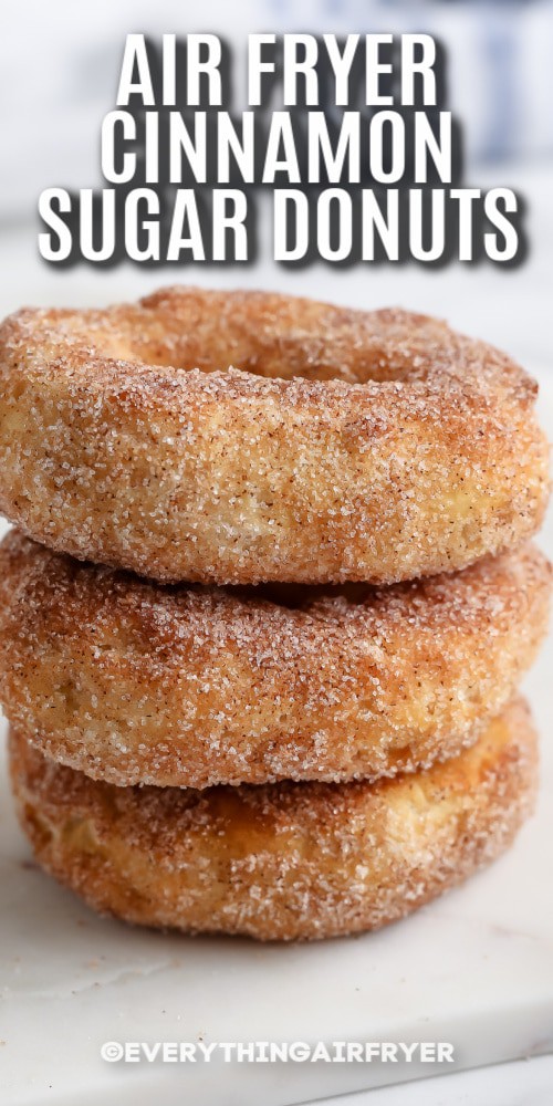 Air Fryer Cinnamon Sugar Donuts stacked on a cutting board with writing.