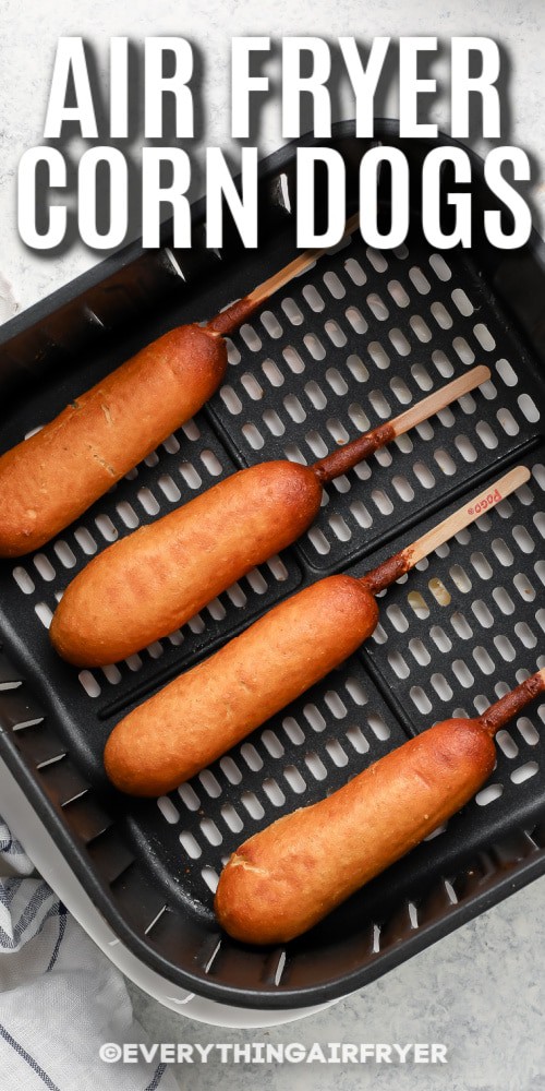 Cooked corn dogs in an air fryer basket with writing