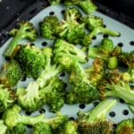 Broccoli in an air fryer basket with writing