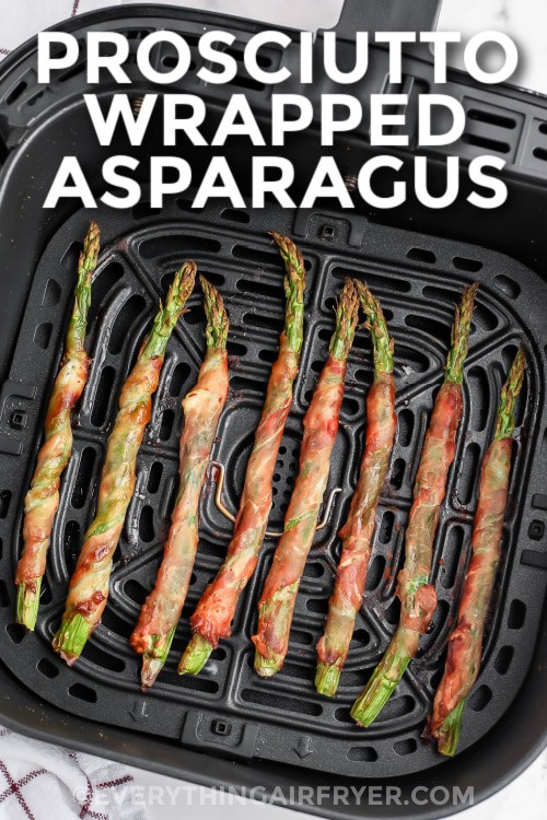 Prosciutto wrapped asparagus in an air fryer basket with writing