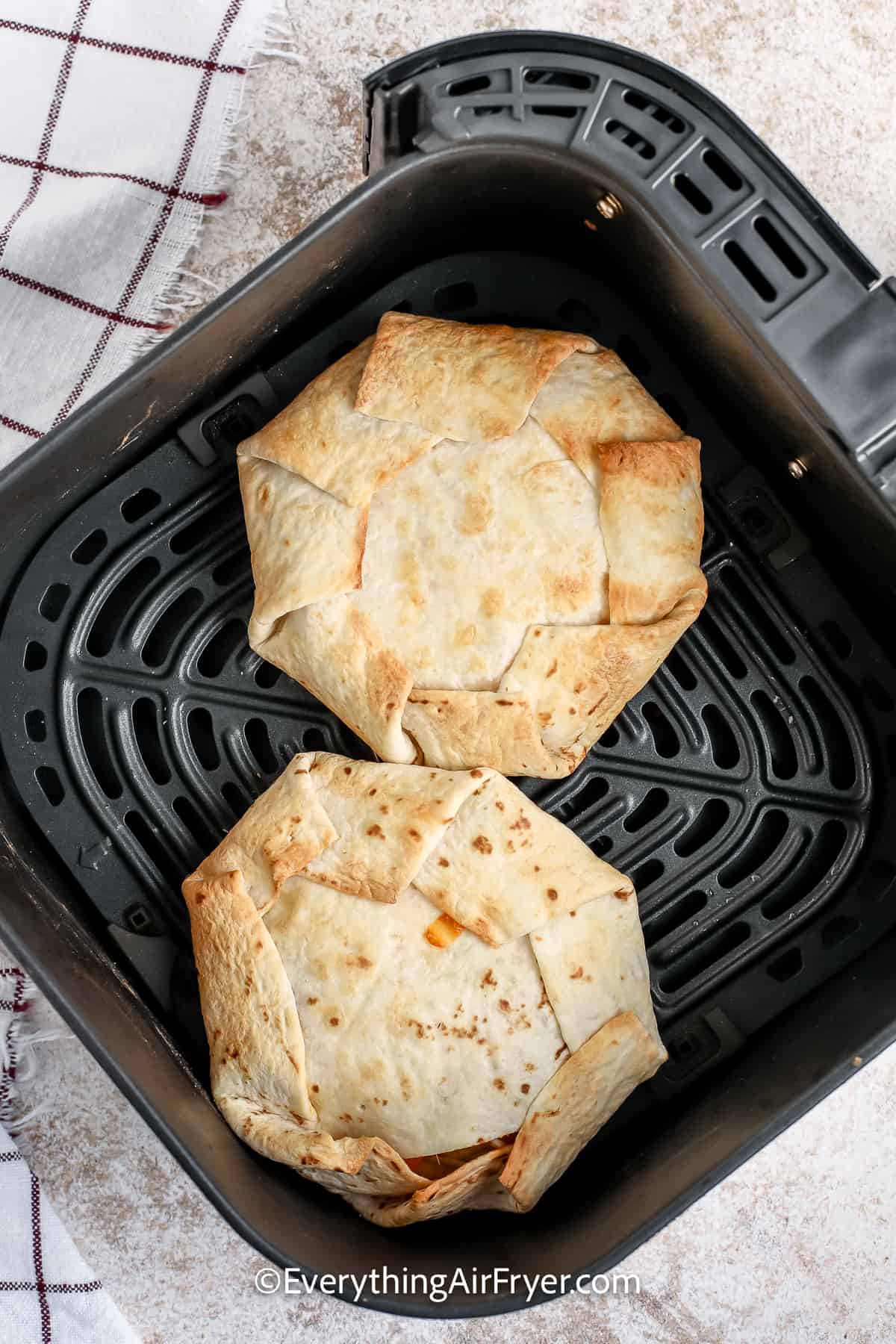 Two crunchwrap supremes cooked in an air fryer basket