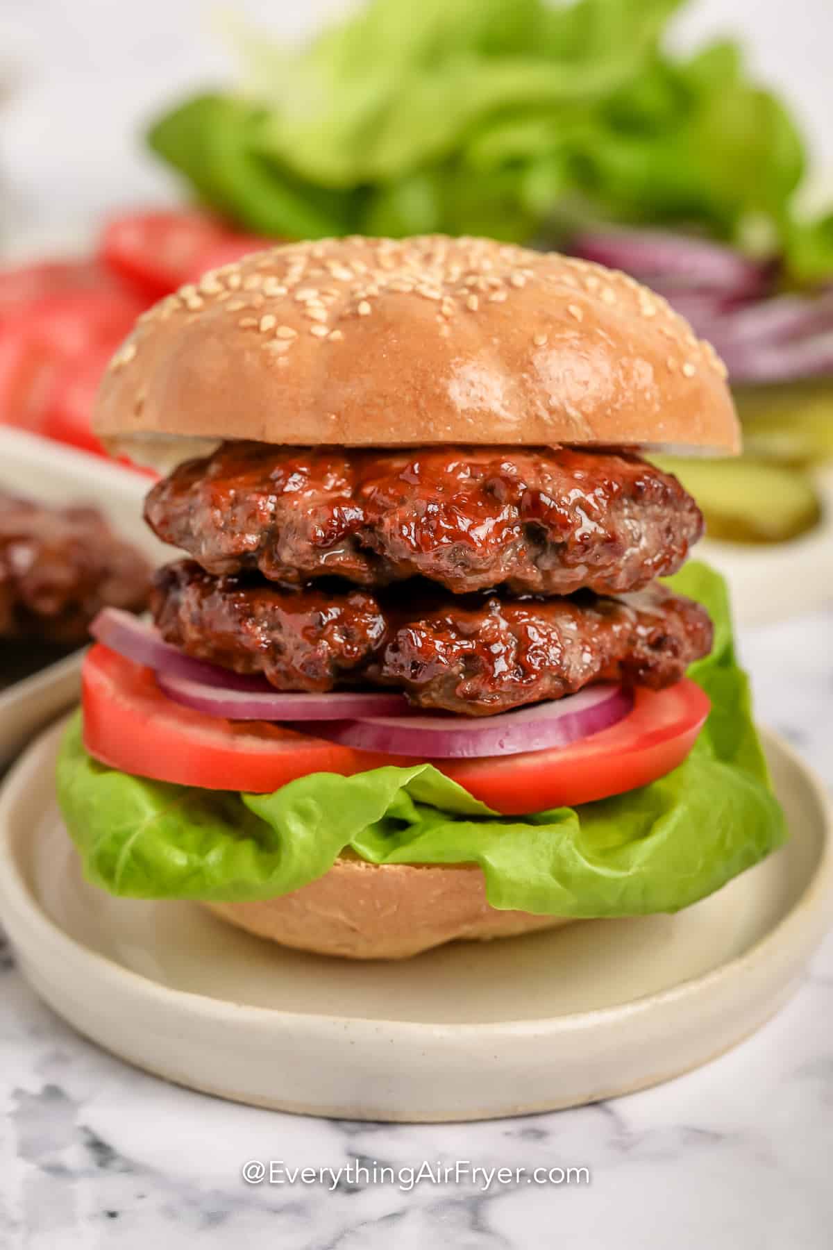 Air fryer burgers on a bun with lettuce and tomatoes