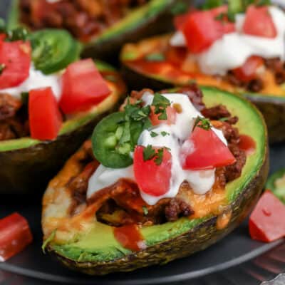 Air Fryer Avocado Boats with sour cream and tomatoes on a plate