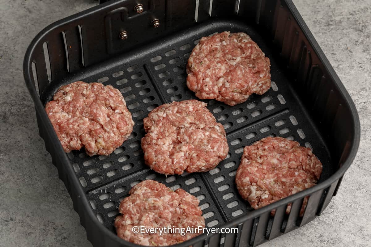 uncooked sausage patties in an air fryer tray