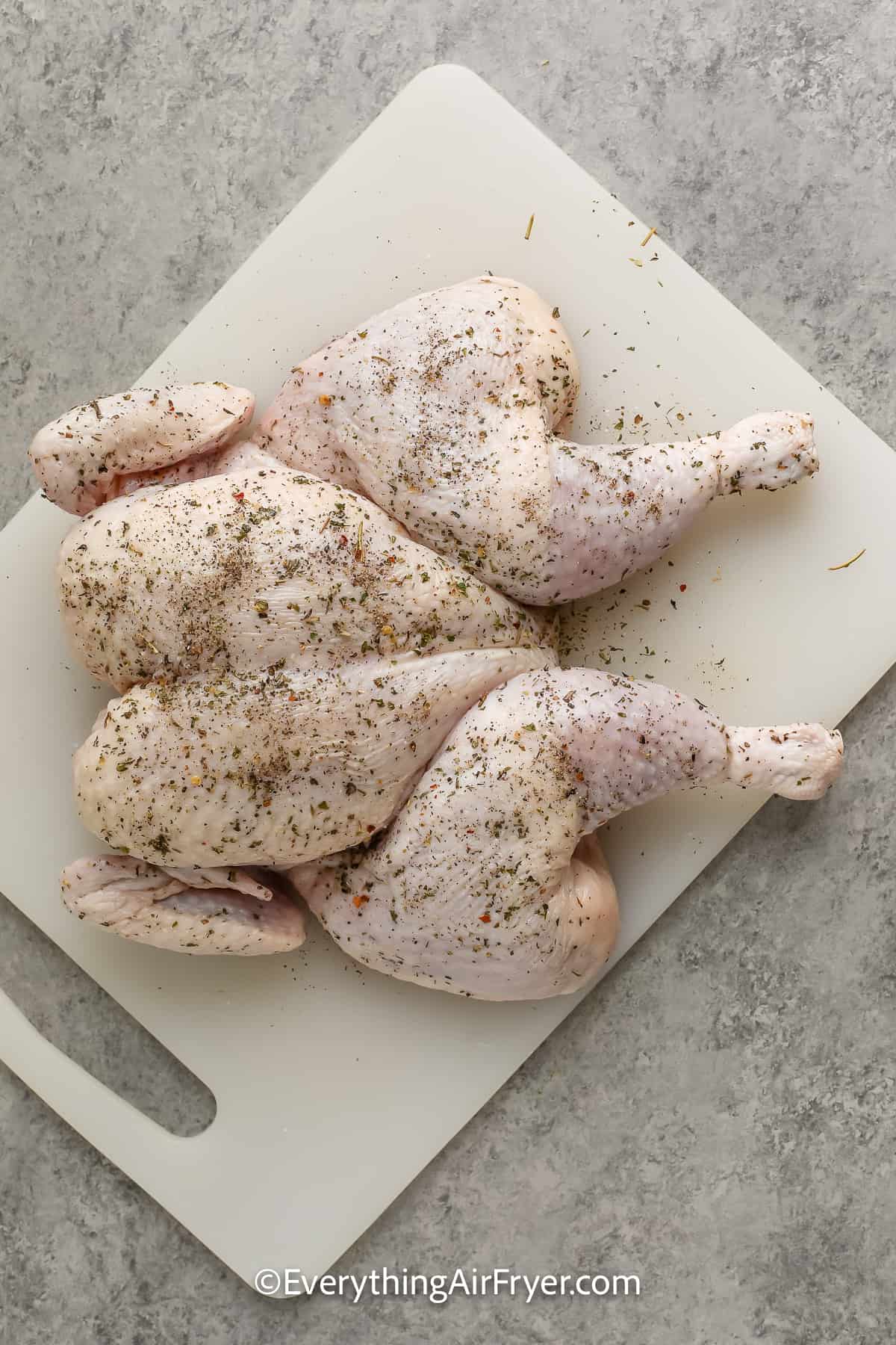 uncooked whole chicken on a cutting board