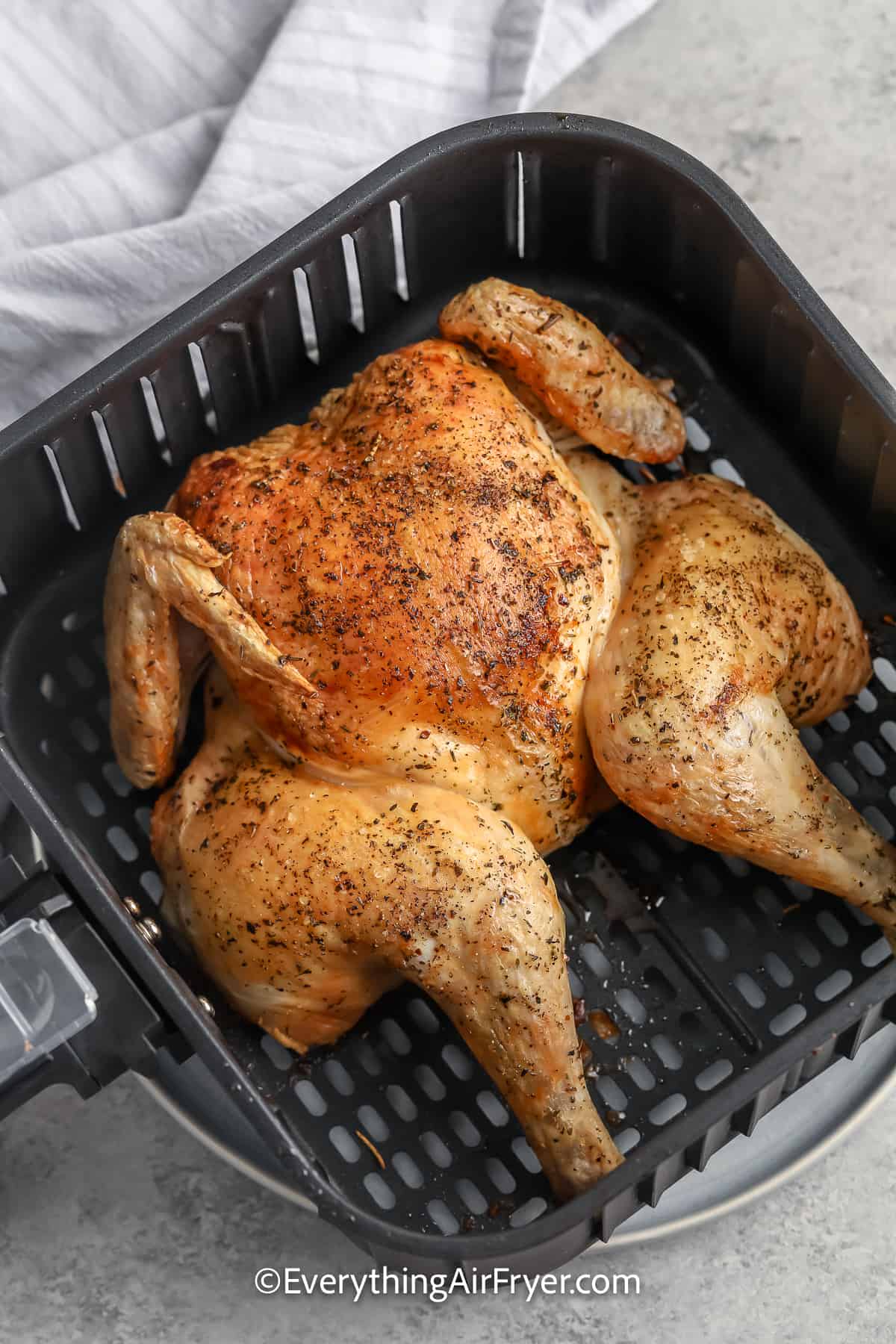 cooked whole chicken in an air fryer tray