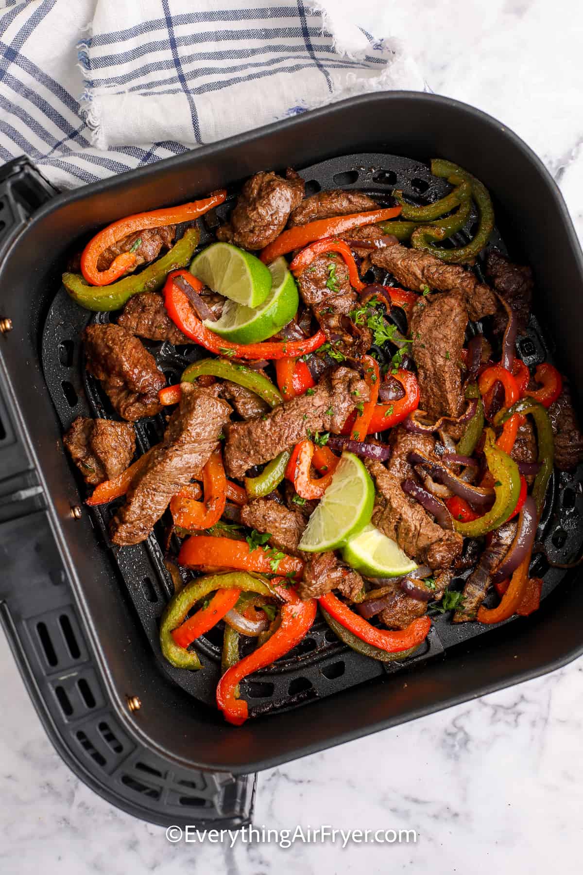 cooked steak, peppers, and onions in an air fryer tray