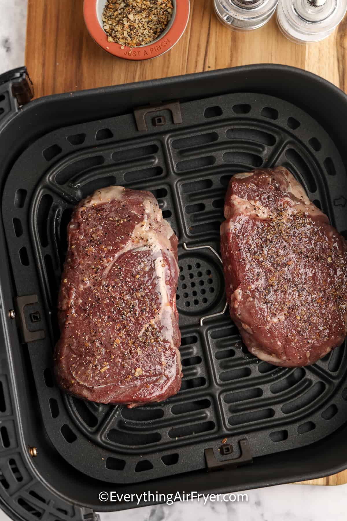 uncooked steak in an air fryer tray