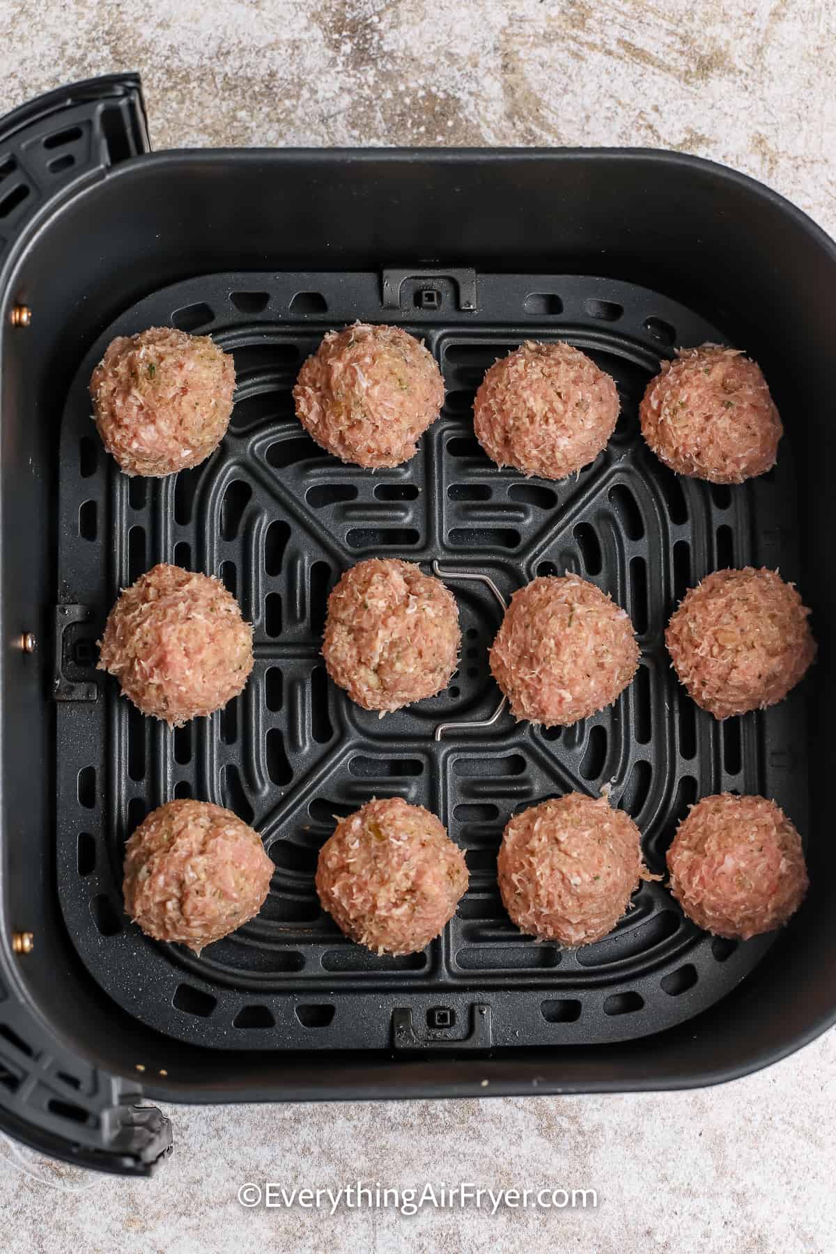 uncooked turkey meatballs in an air fryer tray