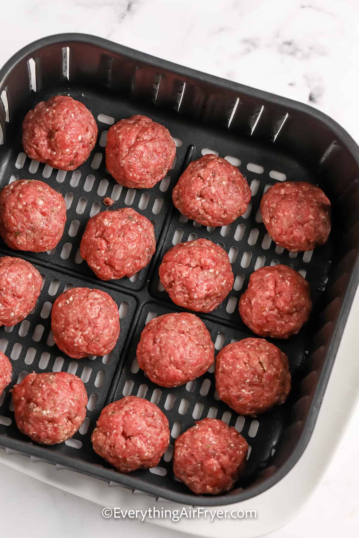 uncooked meatballs in an air fryer tray