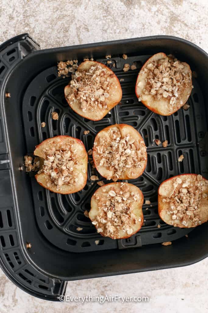 halved apples with topping in an air fryer tray