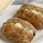 Microwave Baked Potato on a plate cut open and topped with butter and green onions