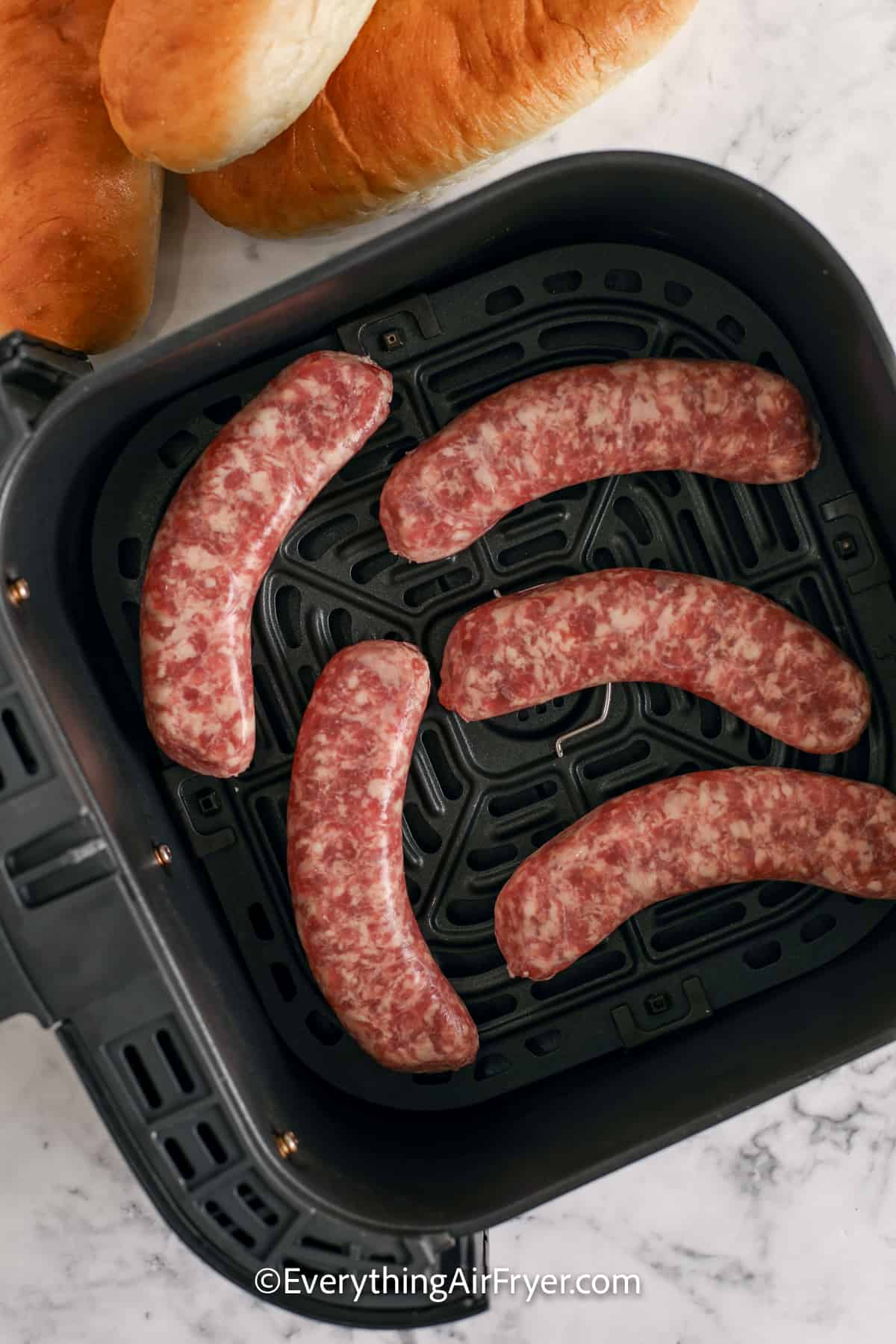 uncooked brats in an air fryer tray