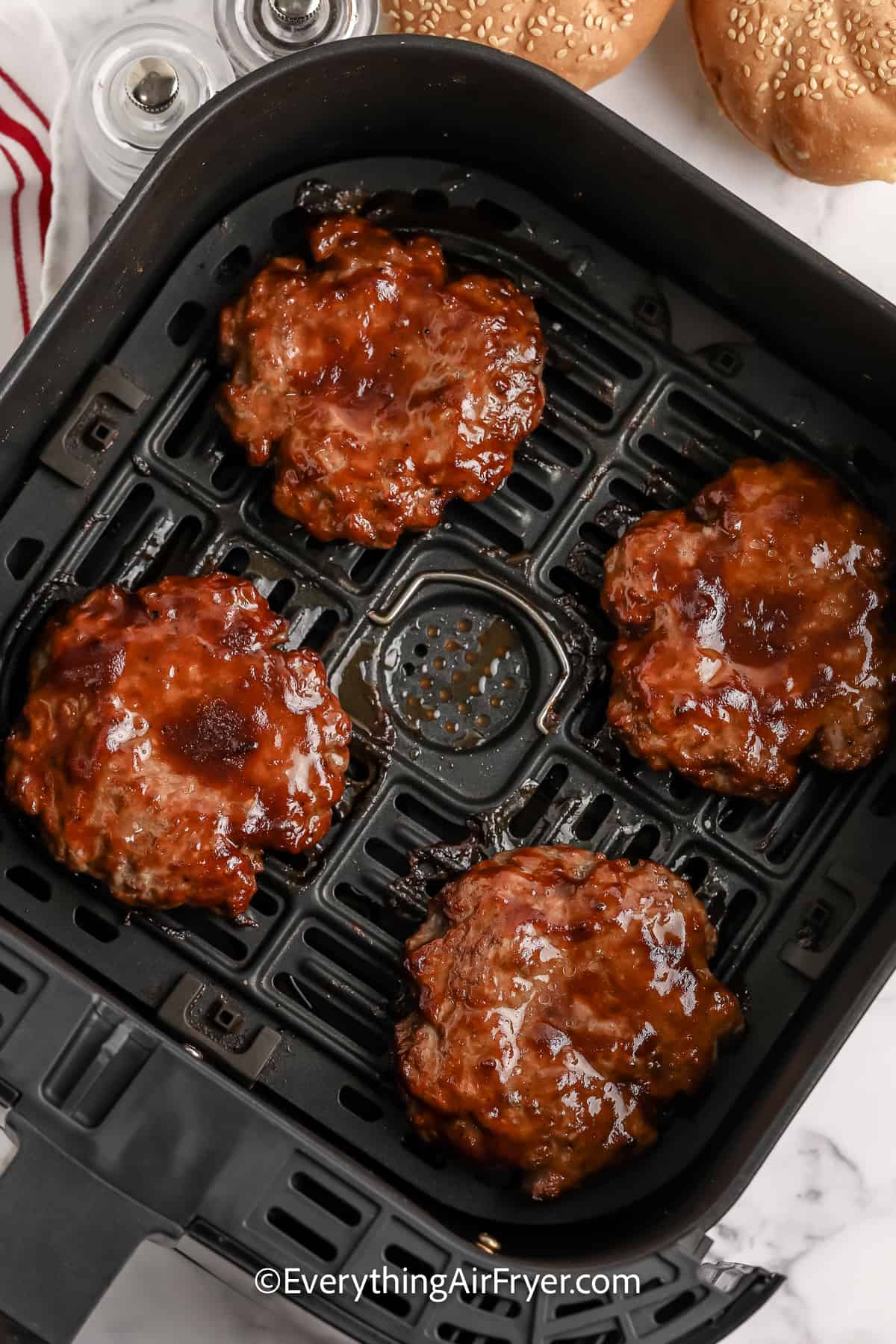 cooked hamburger patties in an air fryer tray