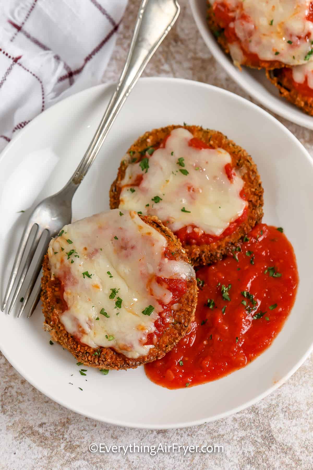 Two slices of Air Fryer Eggplant Parmesan on a plate garnished with parsley
