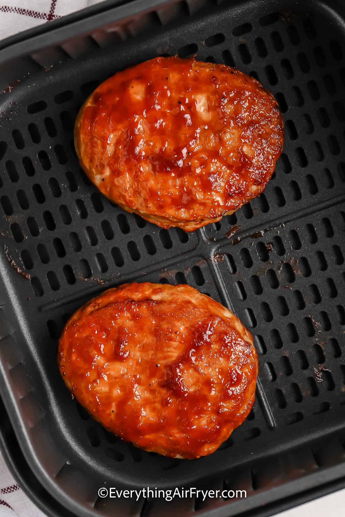 Turkey burgers topped with bbq sauce in an air fryer basket