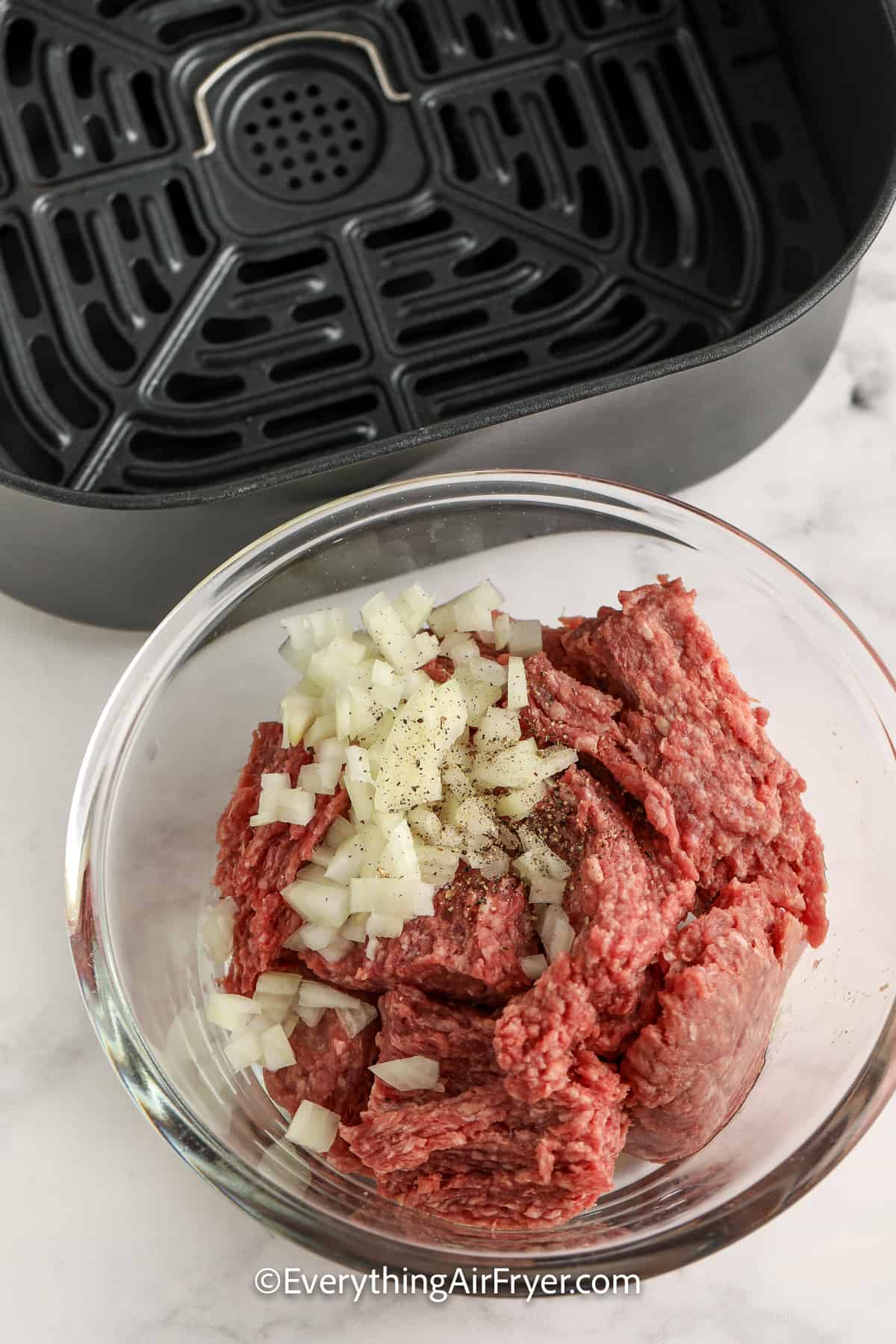raw ground beef in a bowl with diced onions