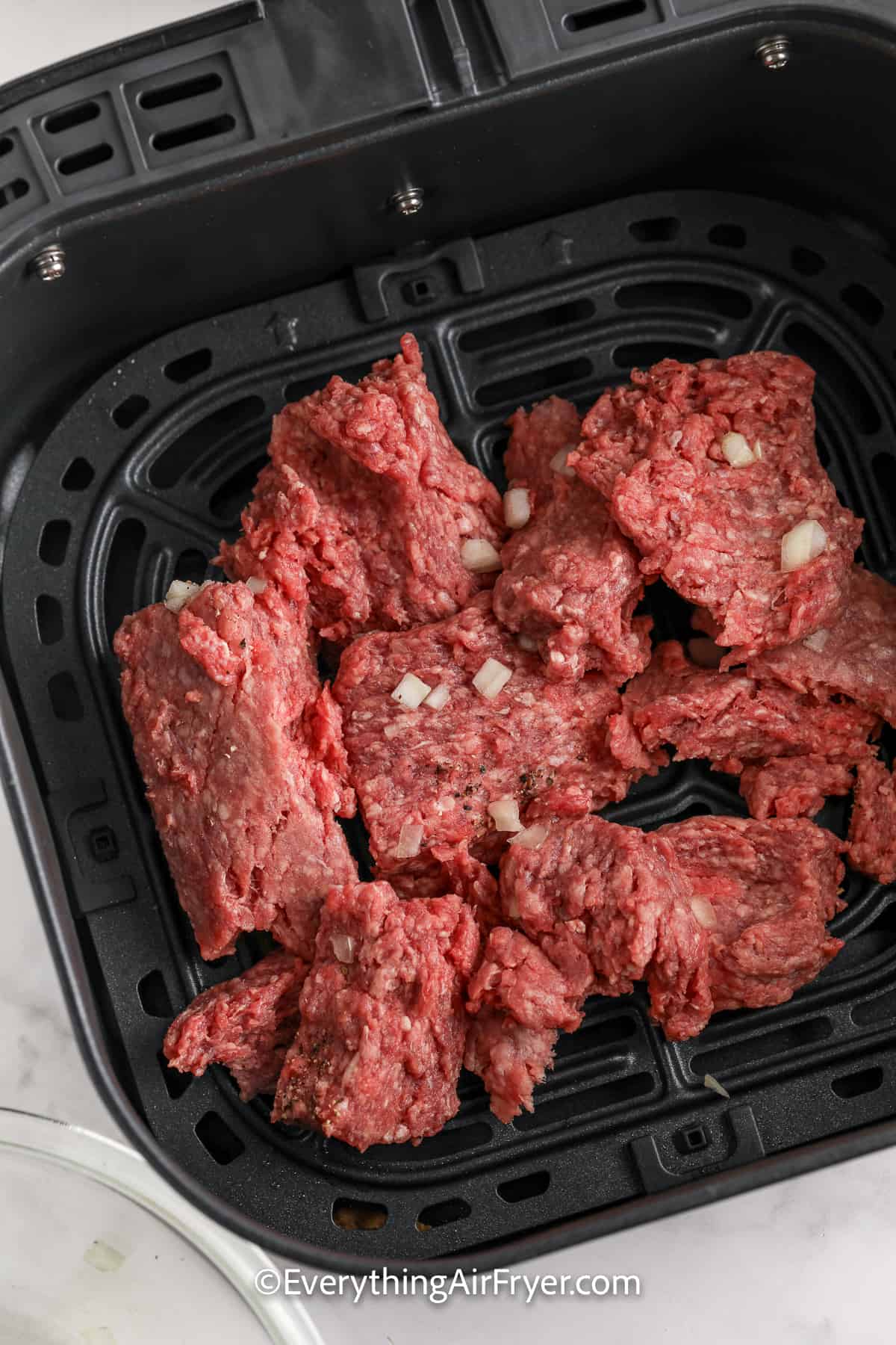 uncooked ground beef in an air fryer tray