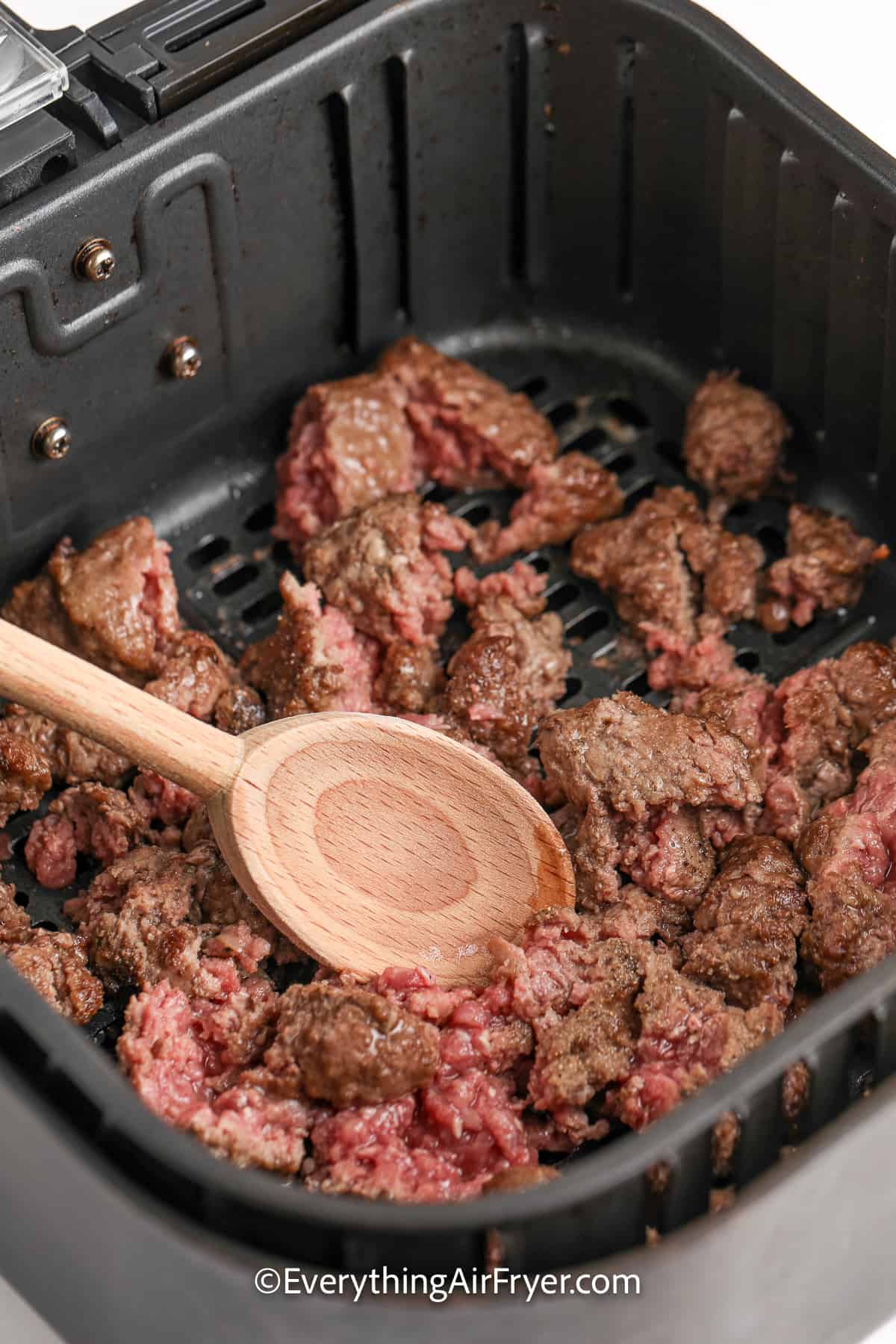 partially cooked ground beef in an air fryer tray
