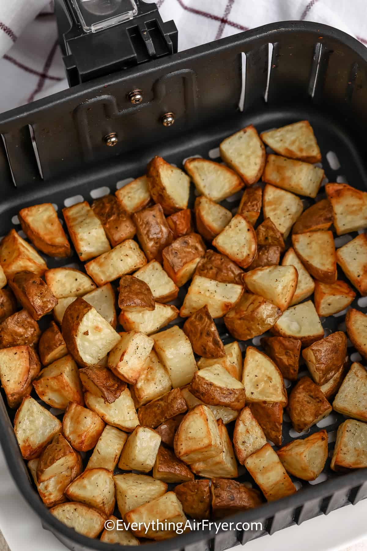 cooked potatoes pieces in an air fryer tray
