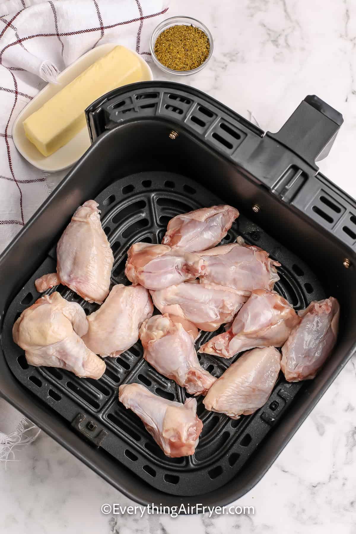 Raw chicken wings in an air fryer basket