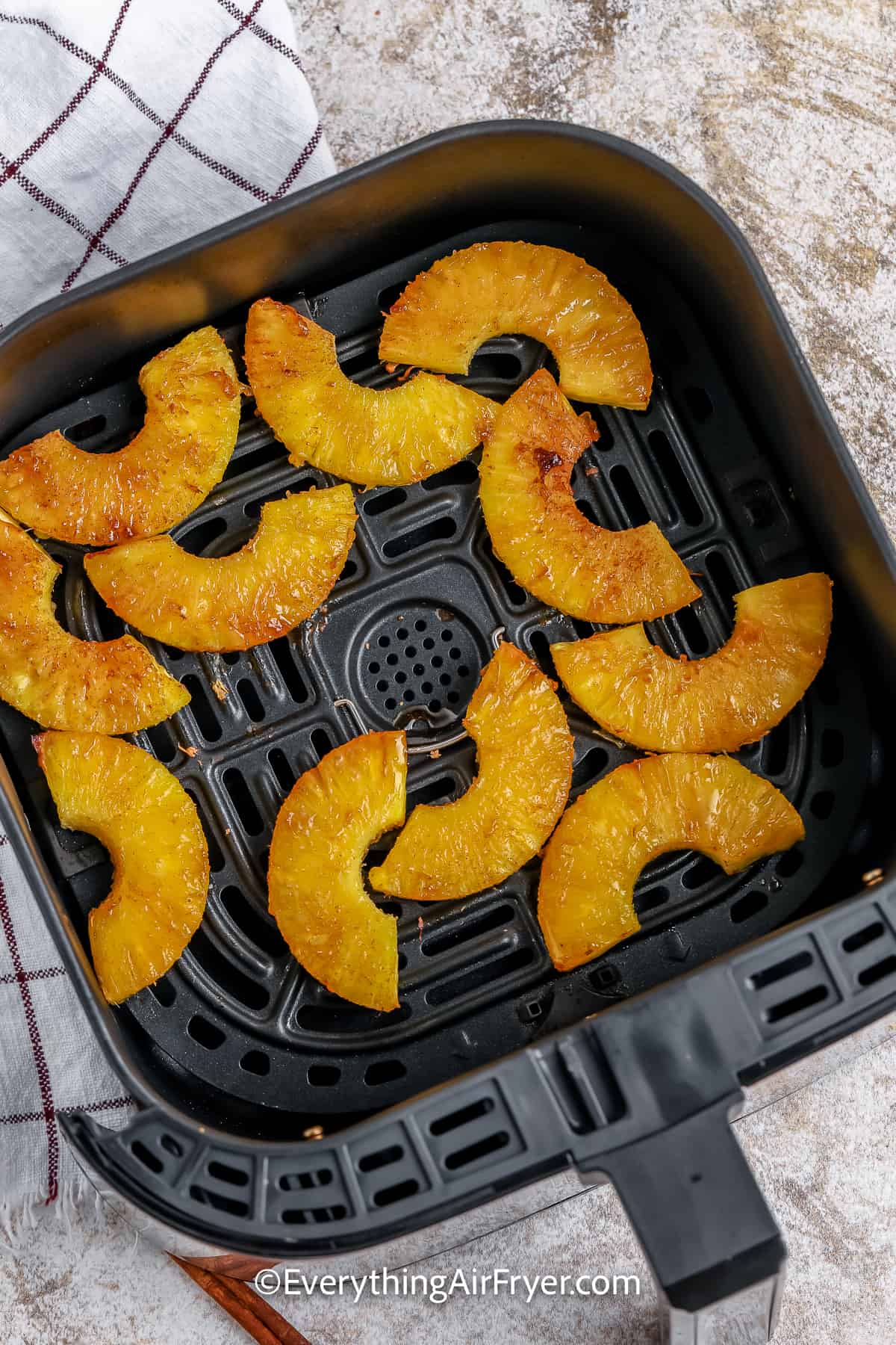 cooked pineapple slices in an air fryer tray