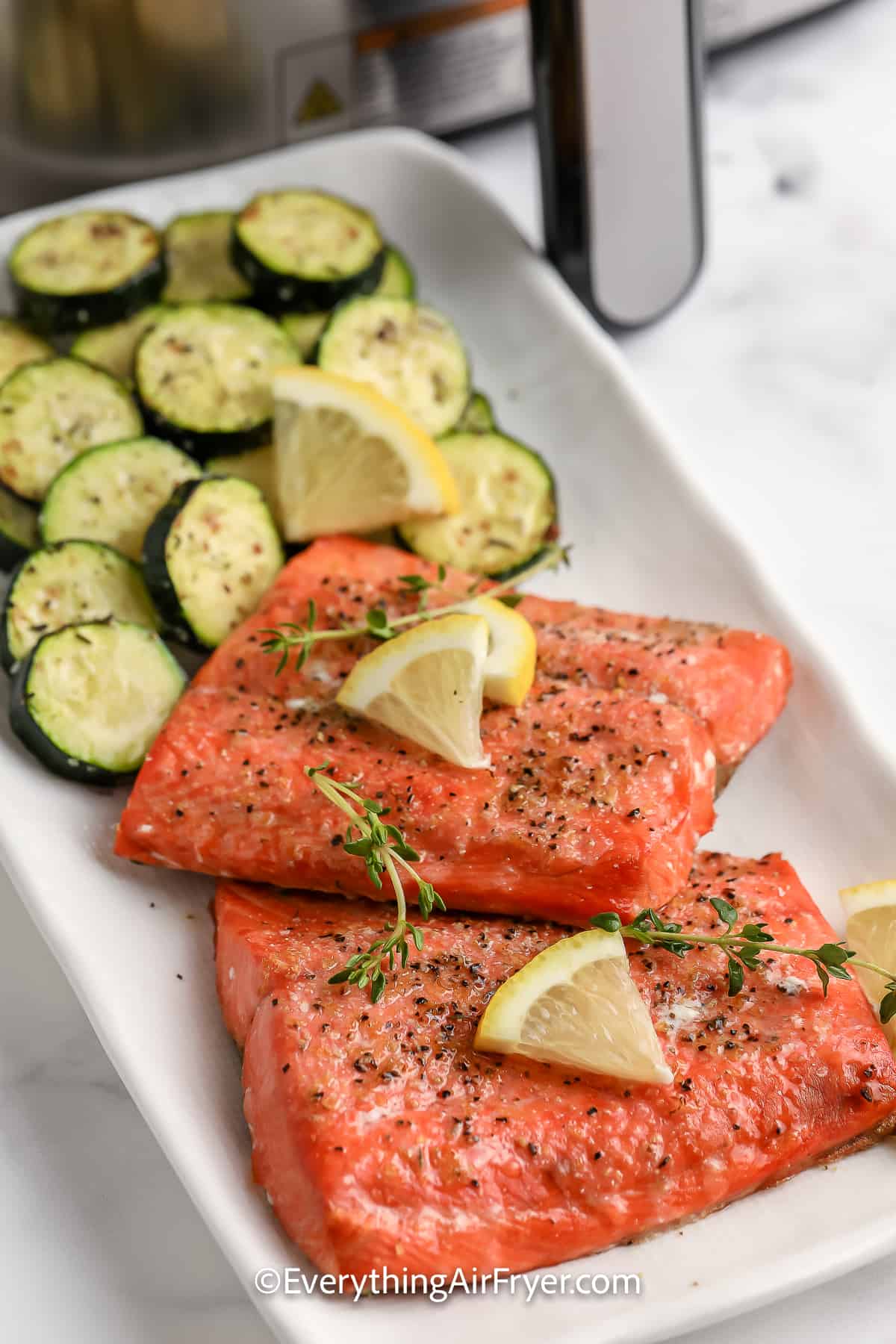 A plate of Air Fryer Salmon and Zucchini garnished with lemons