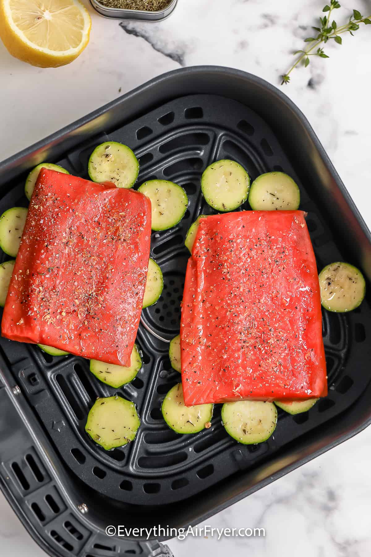 Seasoned Salmon and zucchini in an air fryer basket