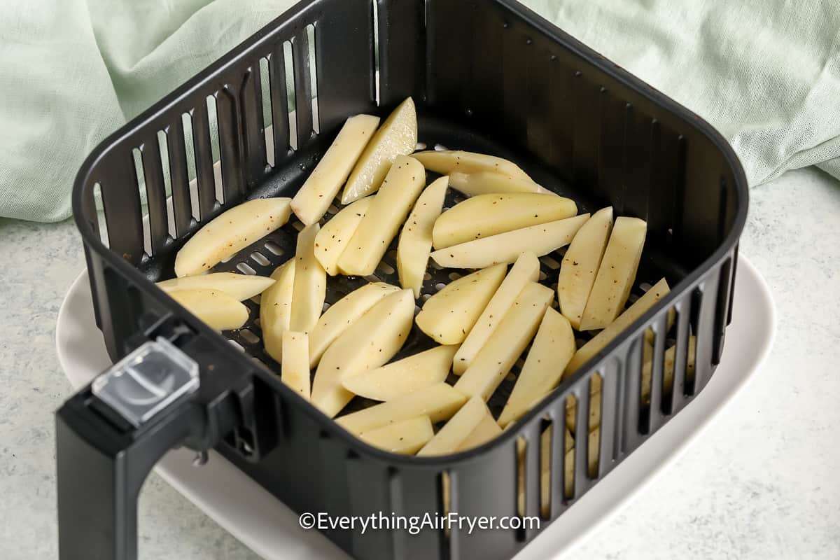 seasoned potato slices in an air fryer basket