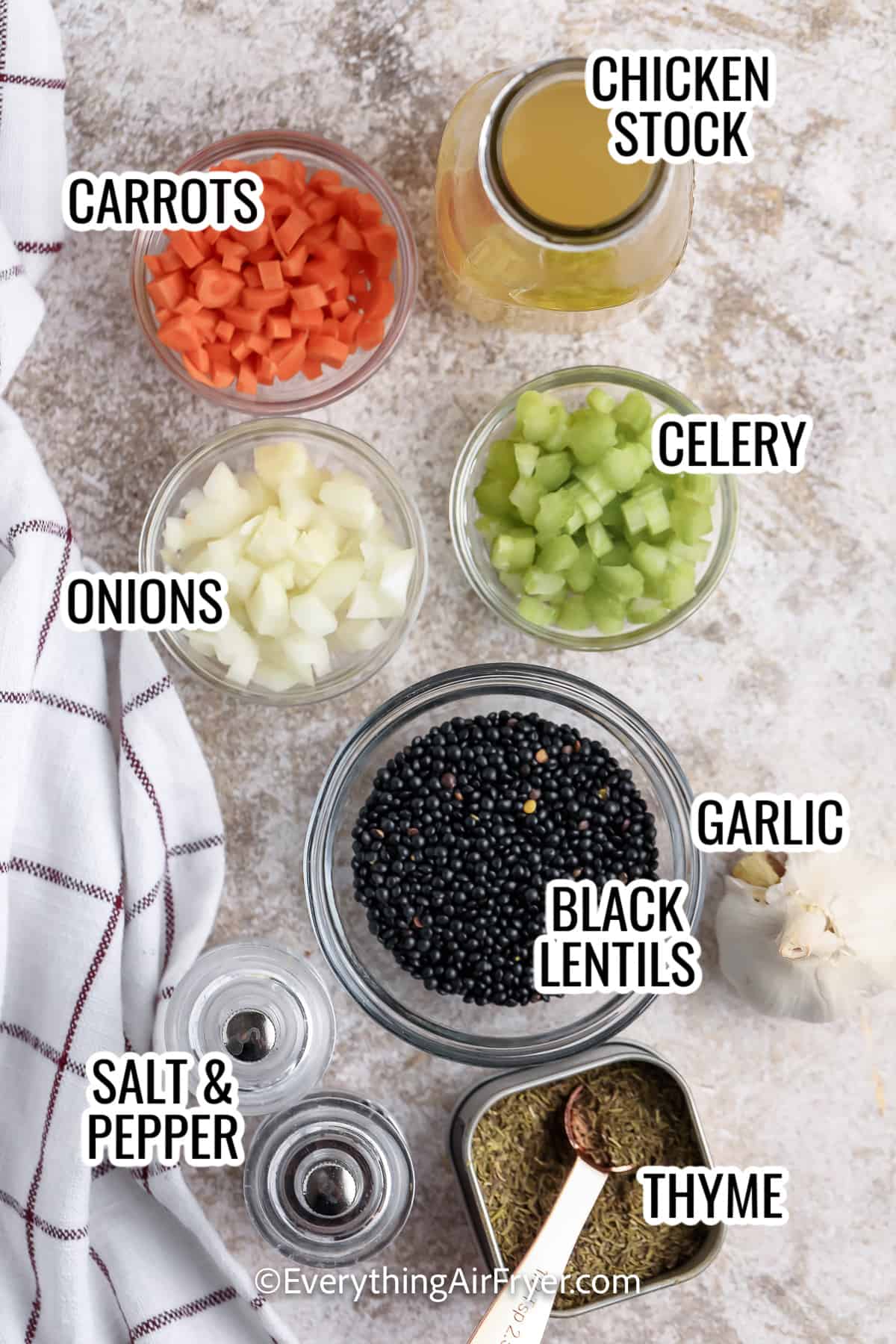 ingredients assembled to make instant pot black lentils, including carrots, onions, celery, chicken stock, garlic, black lentils, thyme, and salt and pepper