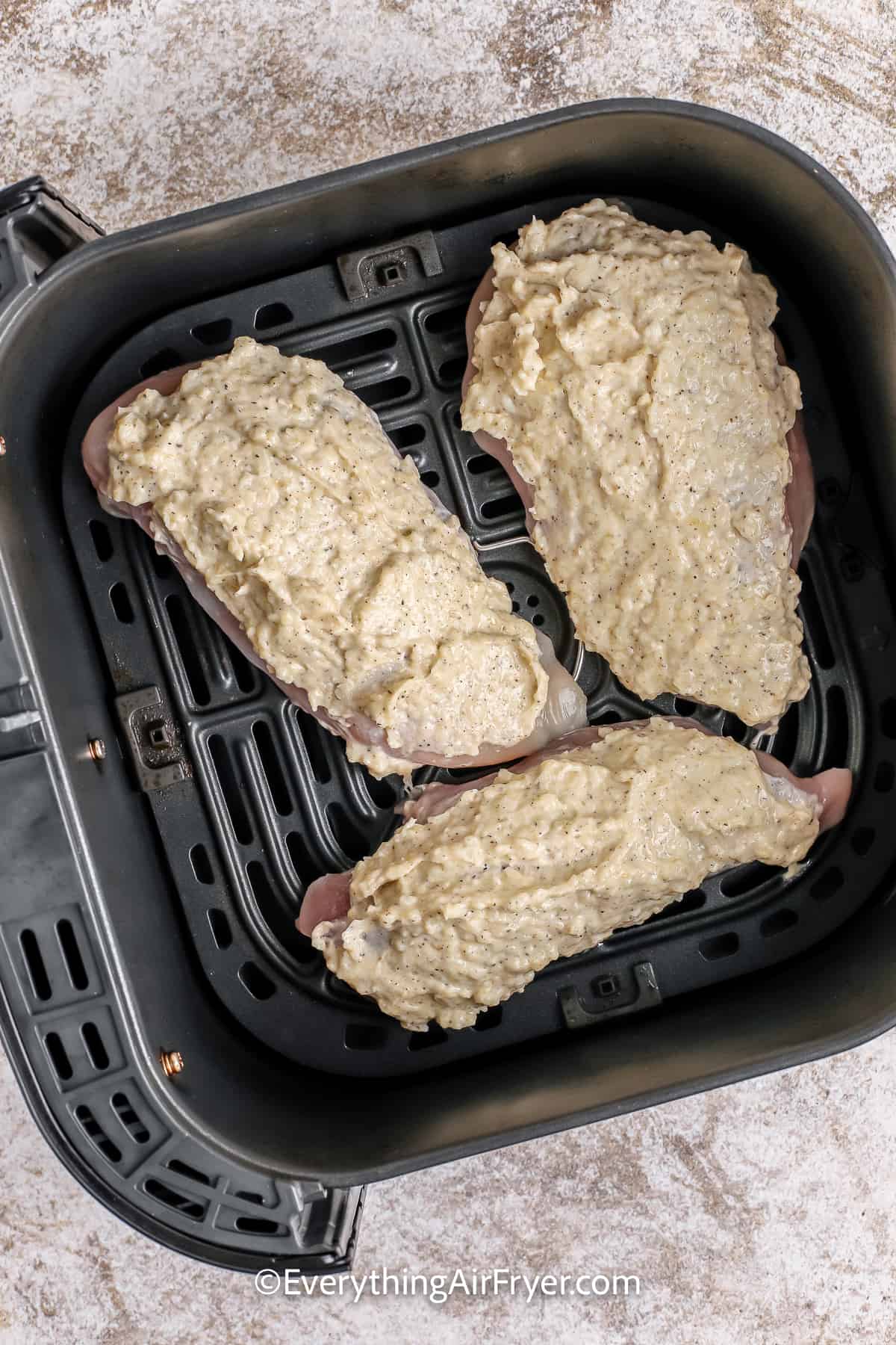 chicken breasts with coating in an air fryer tray
