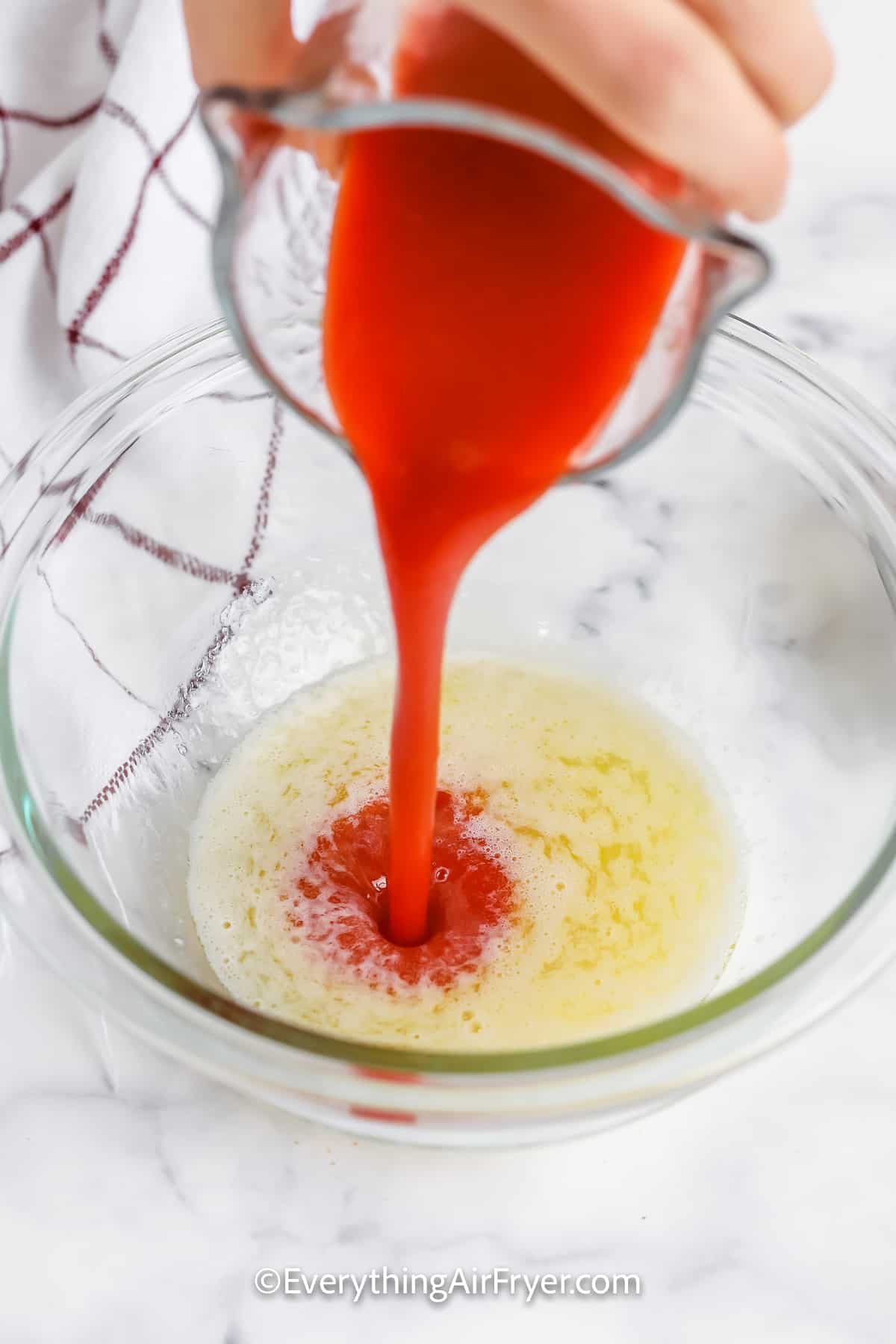 Hot sauce being poured into melted butter