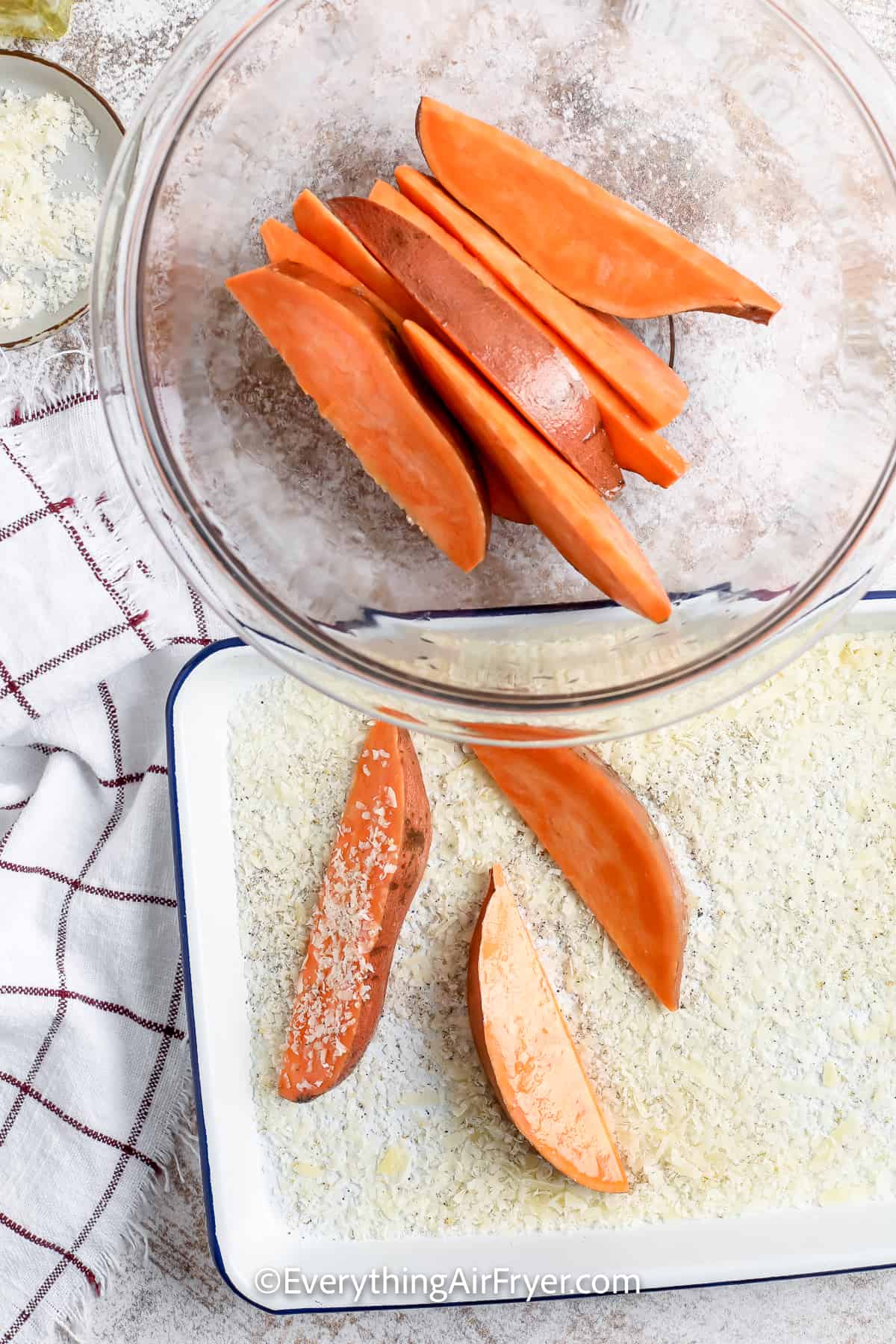 Sweet potato wedges being coated in a parmesan mixture
