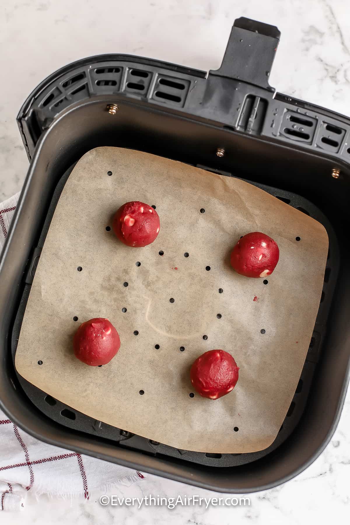 Four Red Velvet Chocolate Chips Cookie dough balls in an air fryer basket