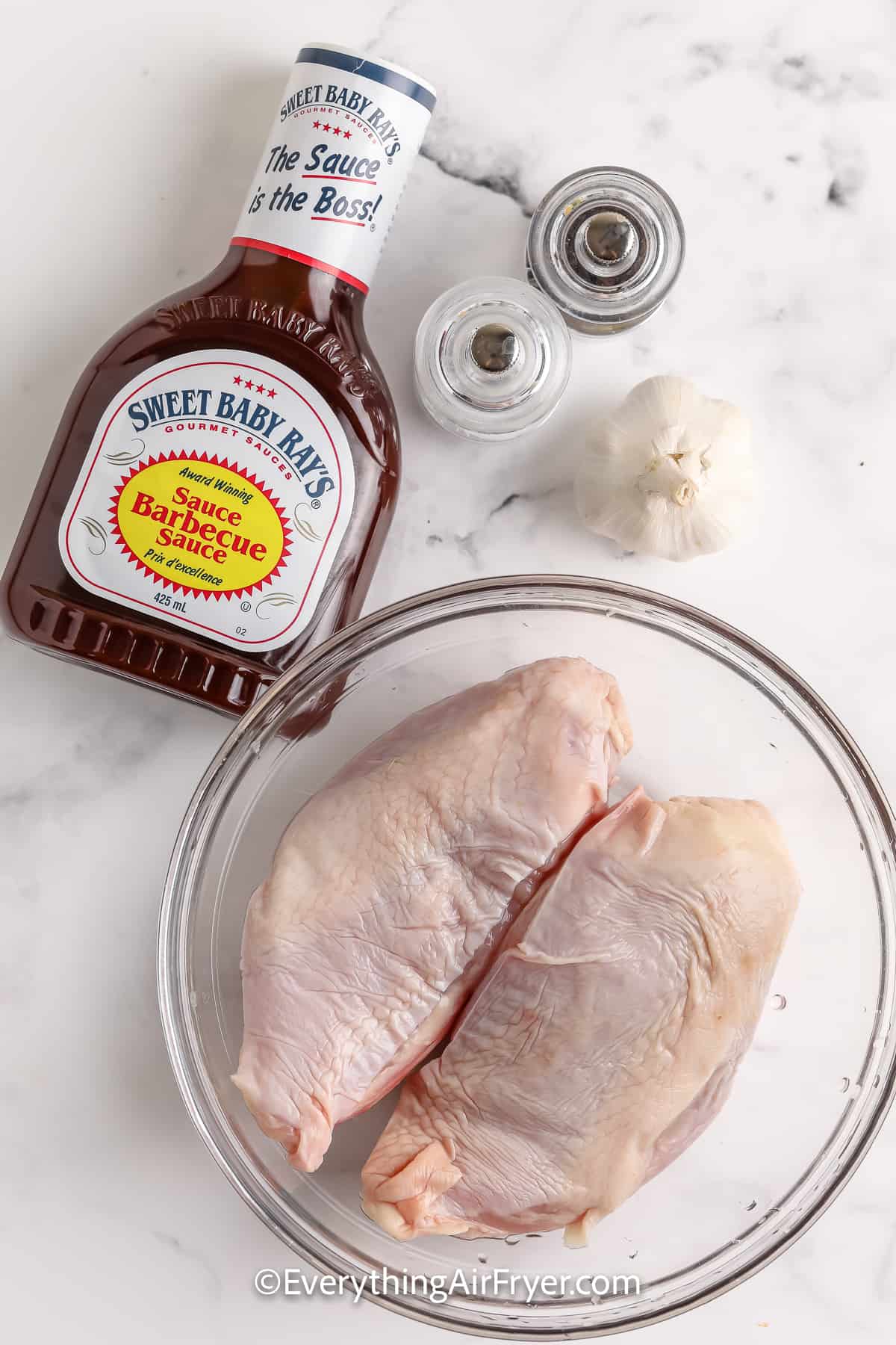ingredients assembled to make Air Fryer BBQ Split Chicken Breasts including bbq sauce garlic, salt and pepper, and chicken breasts