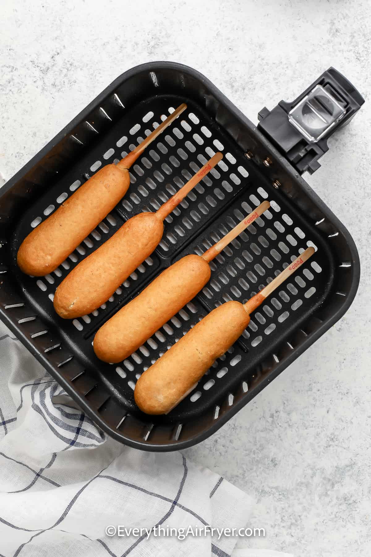 uncooked corn dogs in an air fryer basket