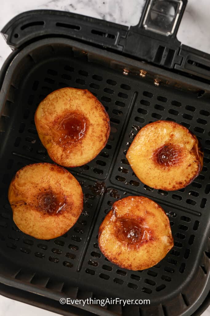 cooked peaches in an air fryer tray