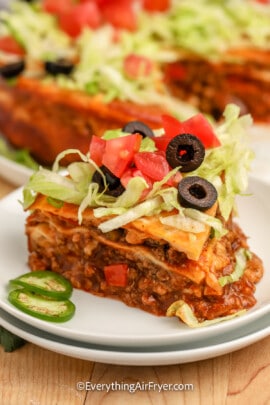 Mexican lasagna topped with lettuce, tomatoes, and olives