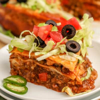 Mexican lasagna topped with lettuce, tomatoes, and olives