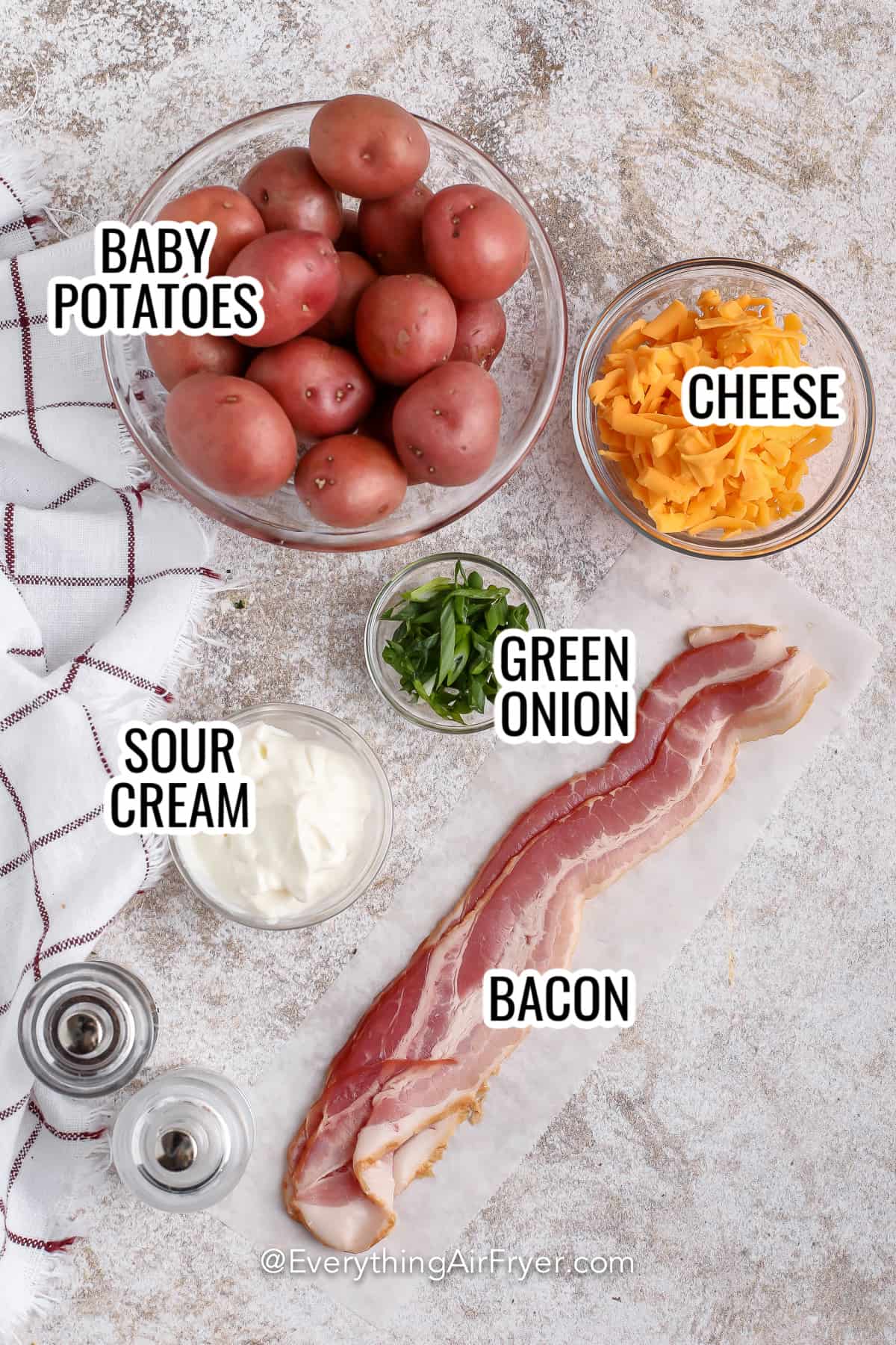 ingredients assembled to make loaded air fryer smashed potatoes, including bacon, baby potatoes, cheese, sour cream, and green onions