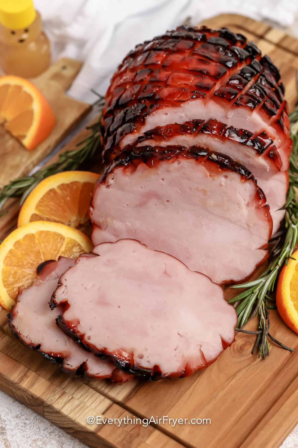 Air Fryer Ham on a wooden board with orange slices & rosemary
